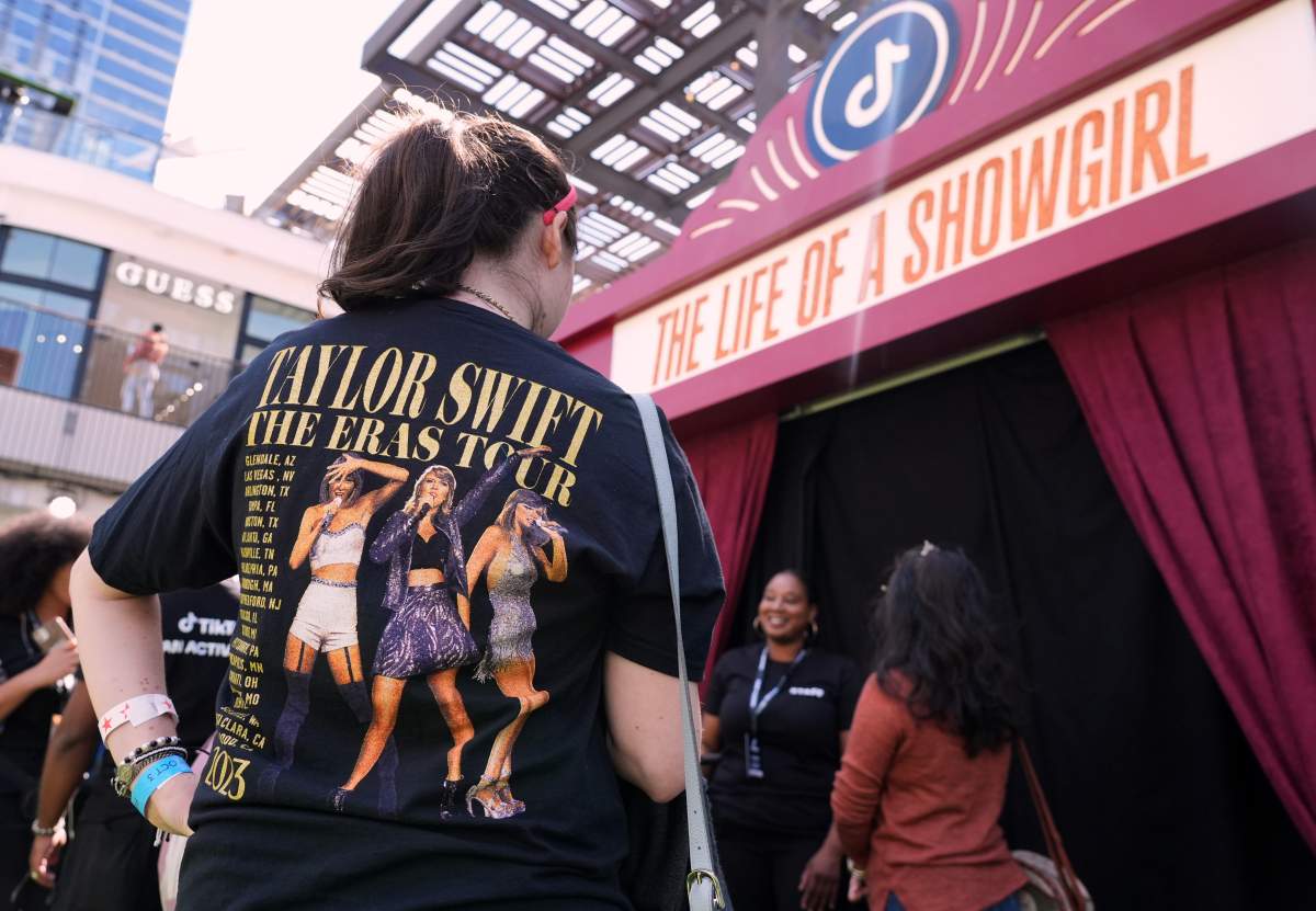 a Taylor Swift fan wearing an Eras Tour T-shirt enters a pop-up